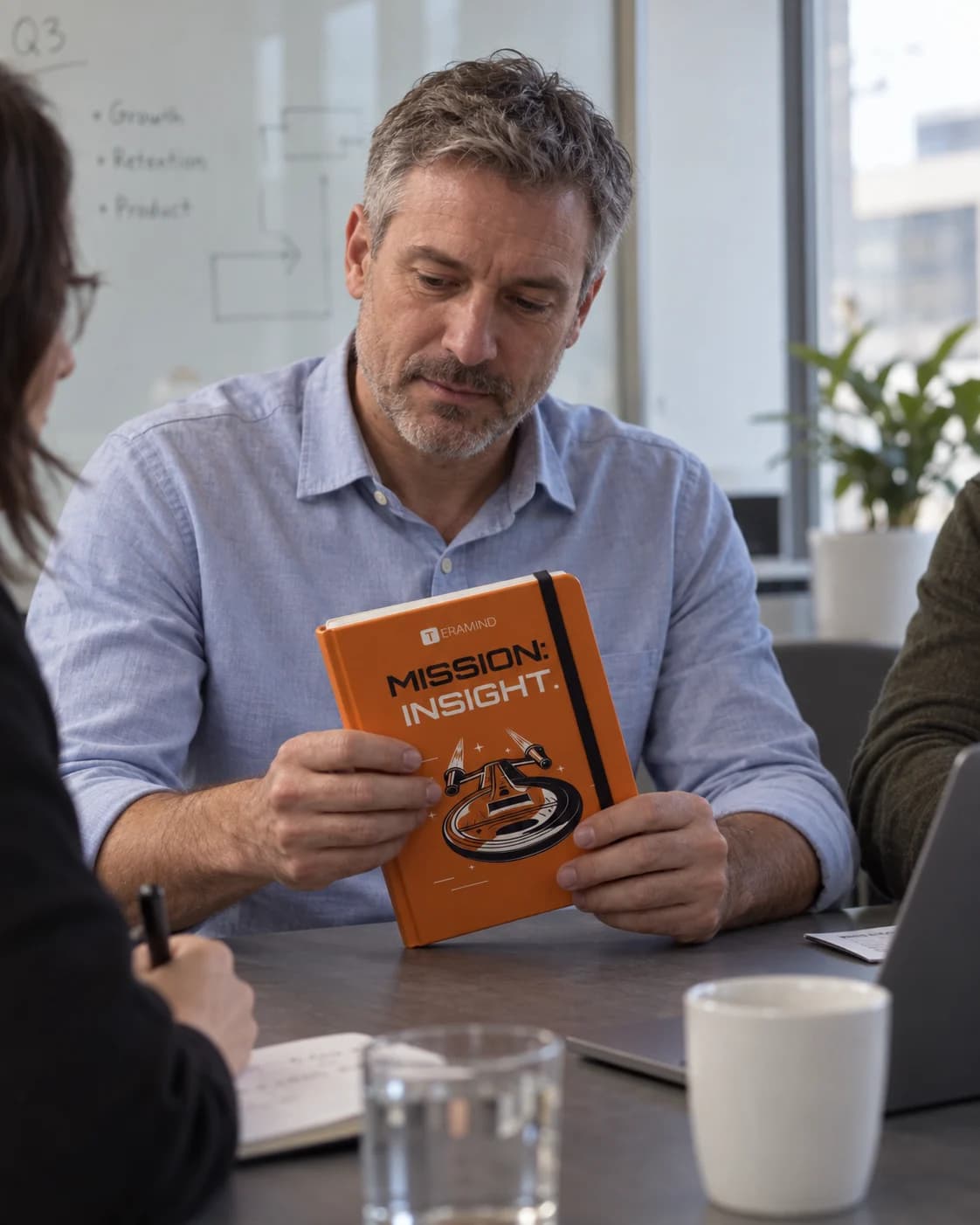 A coworker carrying a Teramind Mission Insight notebook into a meeting.