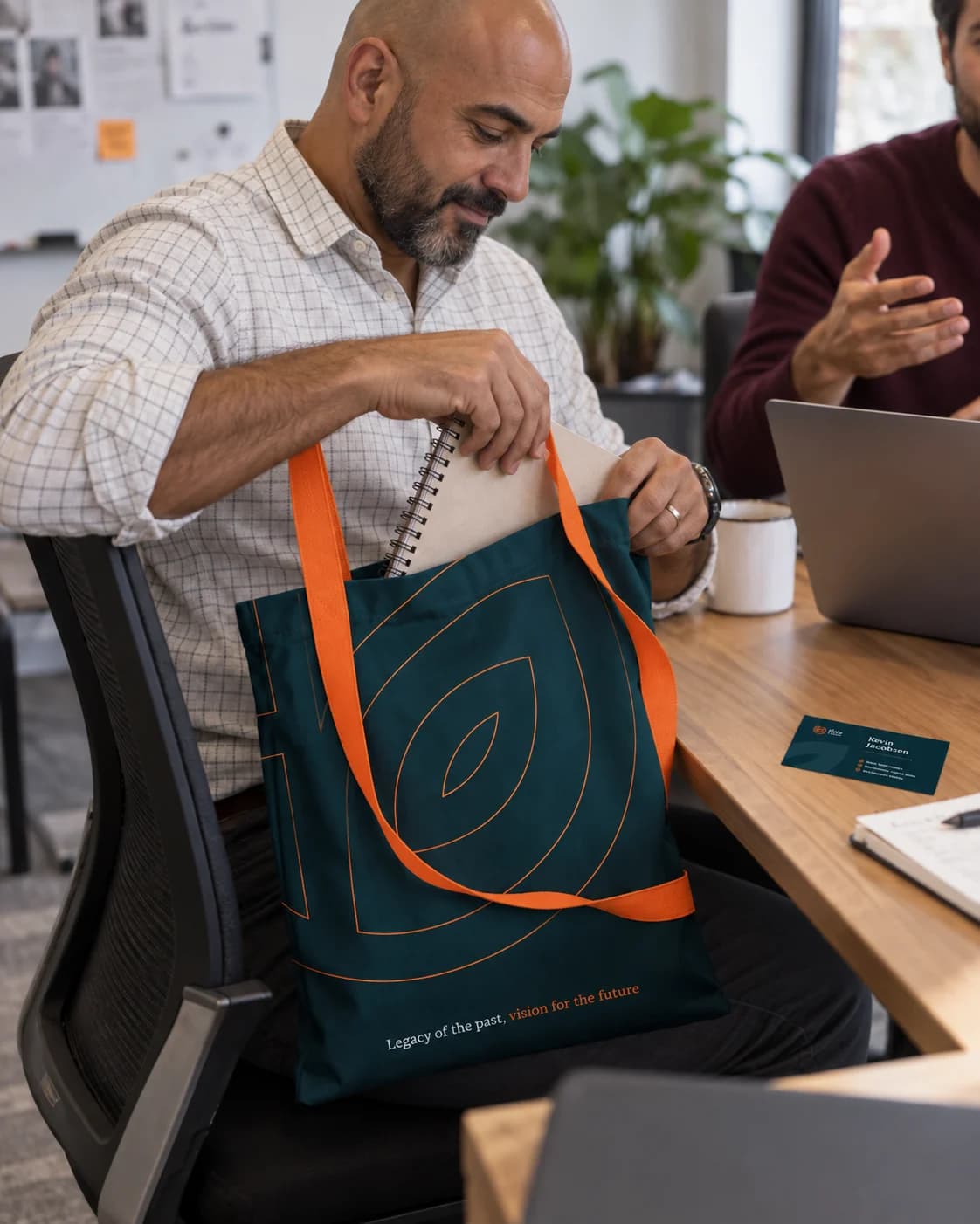 A coworker retrieving a notebook from an HLC Equity tote during a meeting.