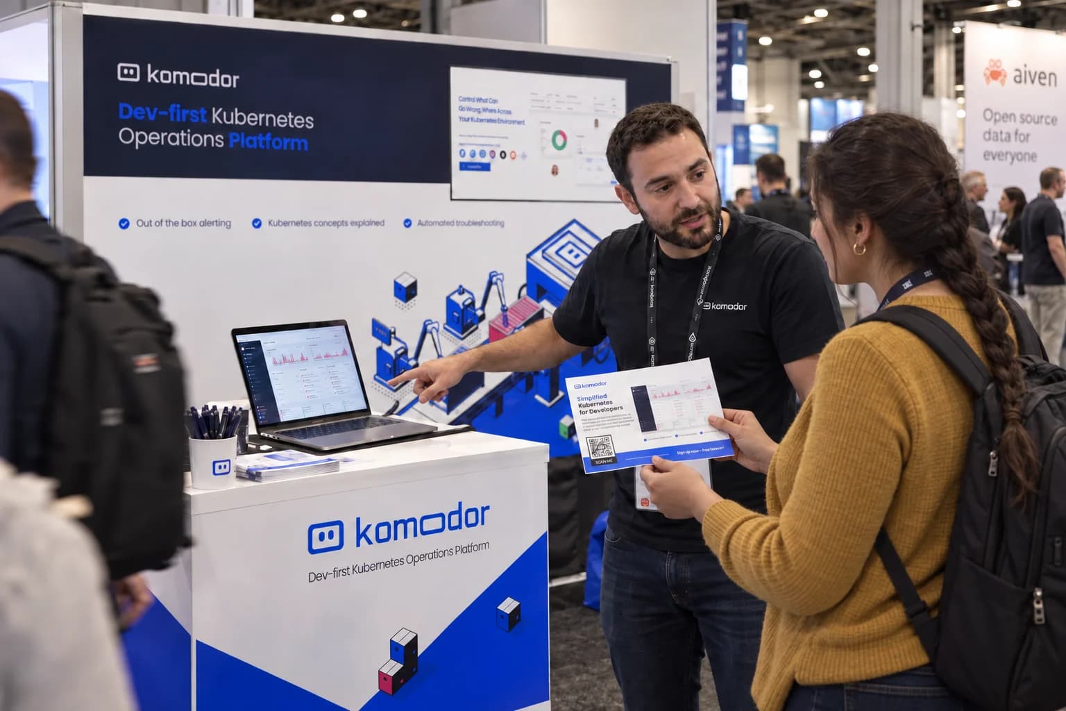 A visitor reading Komodor materials during a booth demonstration.