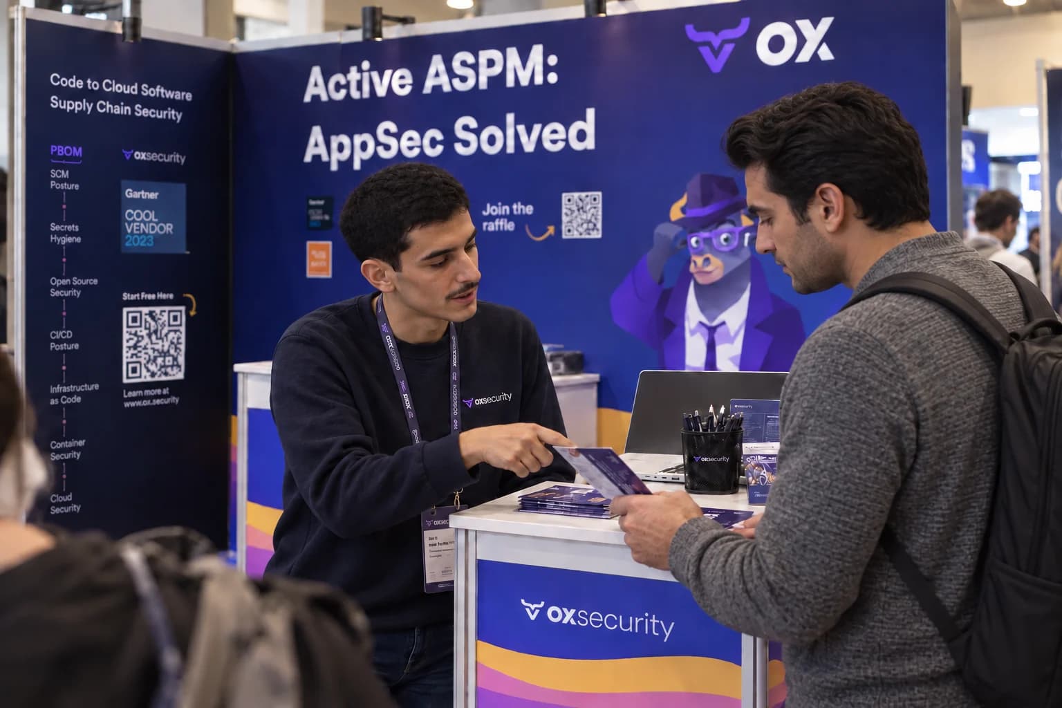 Two distinct people discussing printed materials at the OX Security booth.