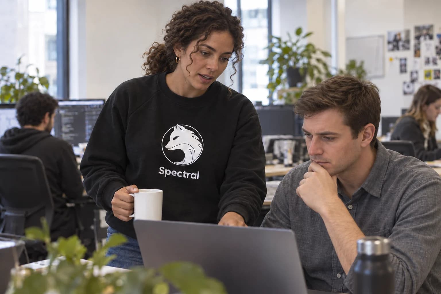 Two distinct coworkers discussing work, one wearing the Spectral sweatshirt.