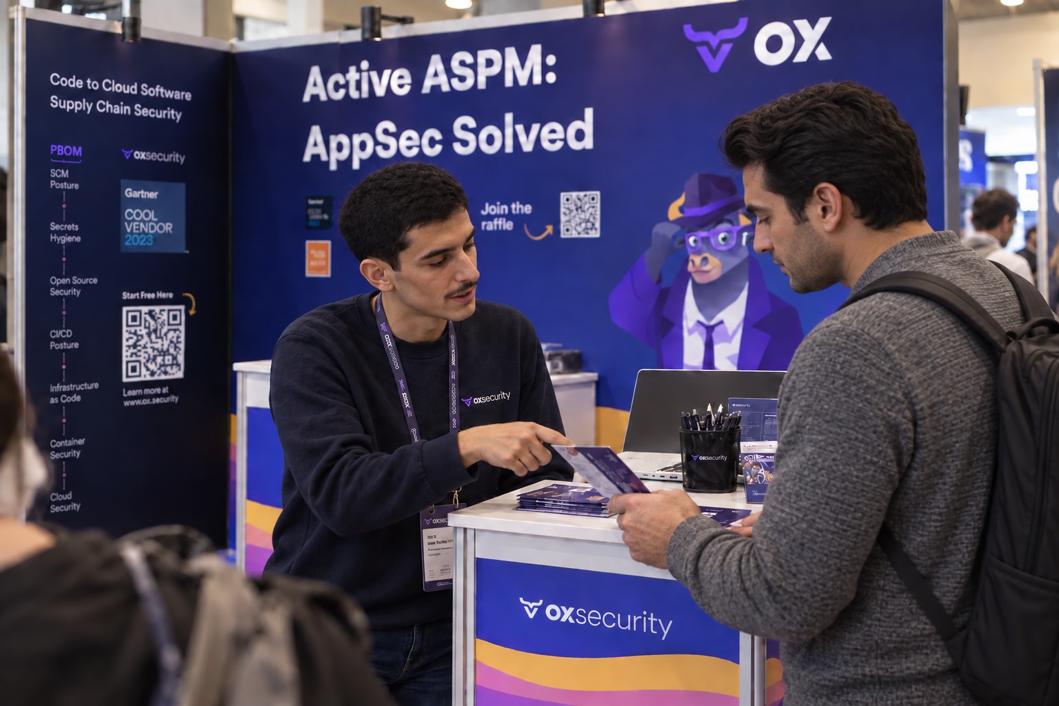 Two distinct people discussing printed materials at the OX Security booth.