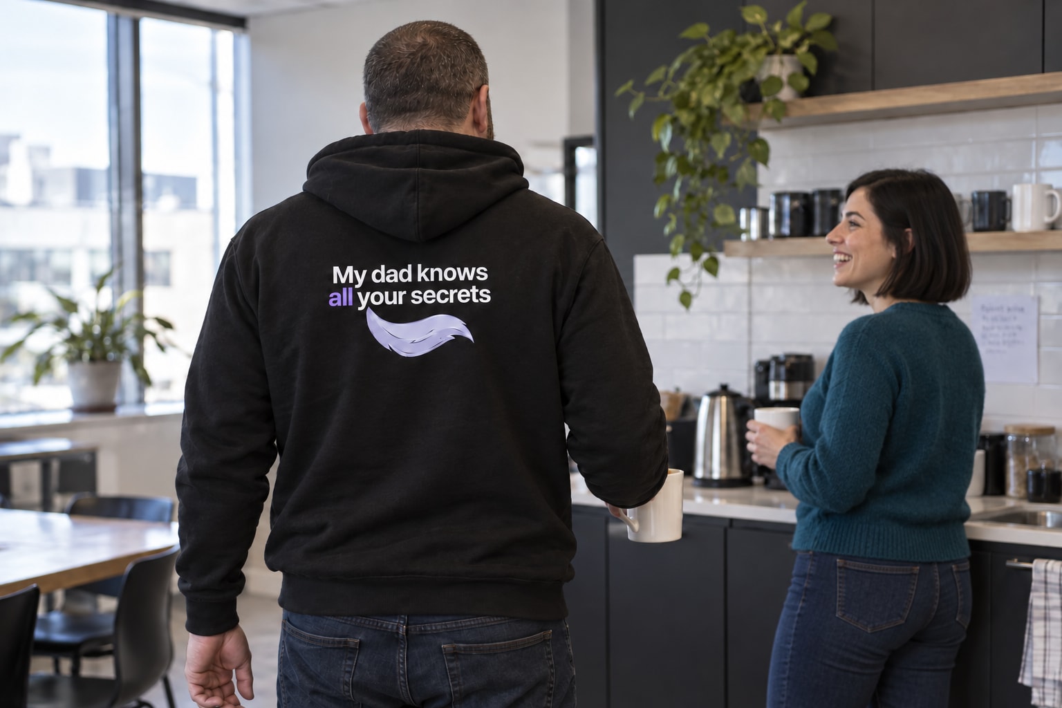 A Spectral hoodie back design worn by a coworker chatting near the office kitchen.