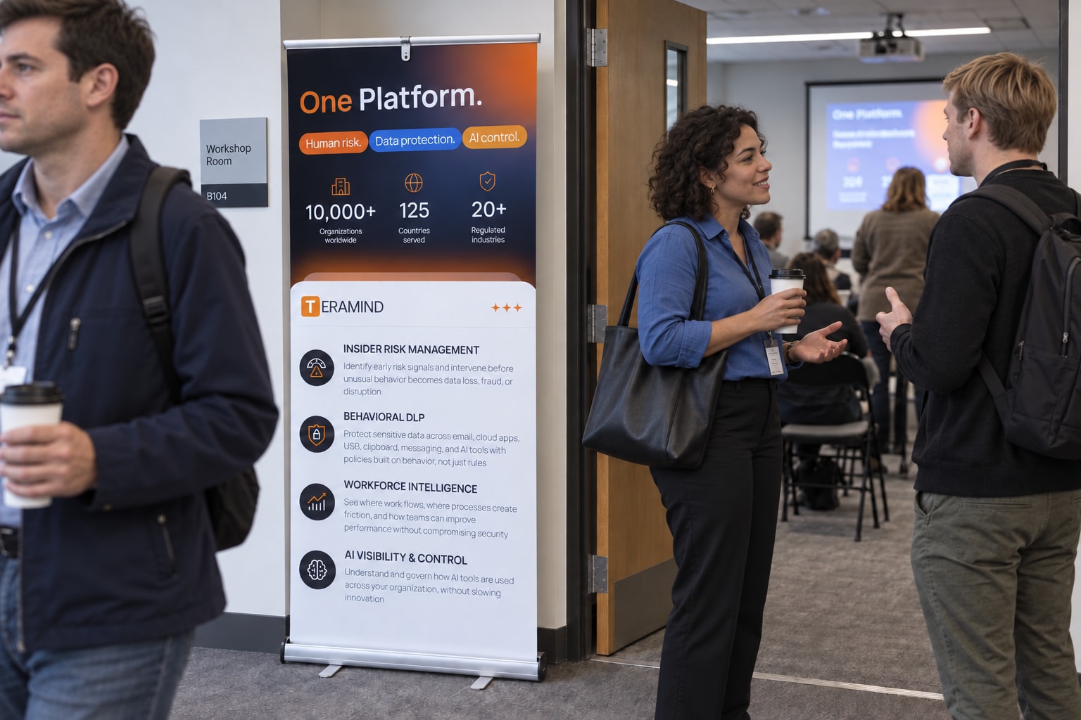 Different attendees arriving at a workshop beside a Teramind roll-up.