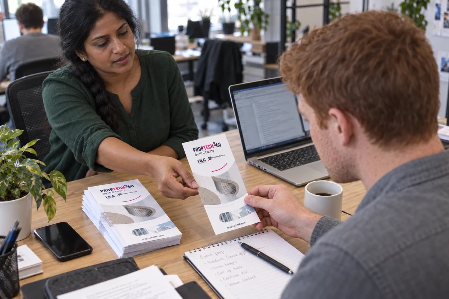 Two coworkers with distinct faces exchanging a PropTech360 printed handout.