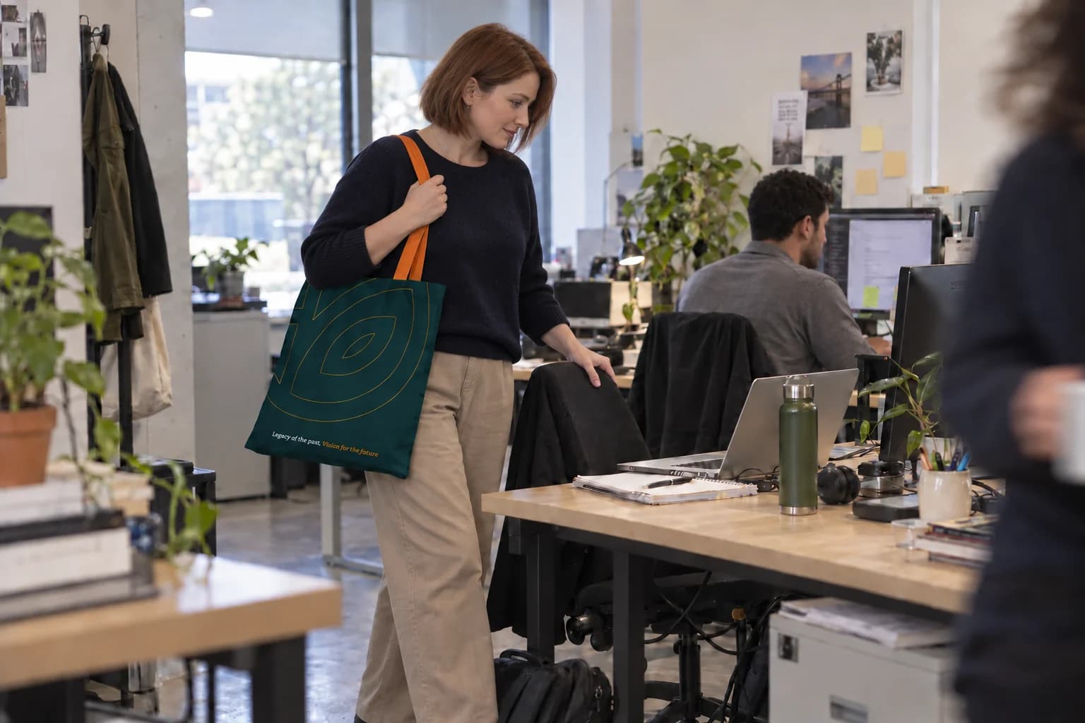 A coworker arriving at her desk with an HLC Equity tote.