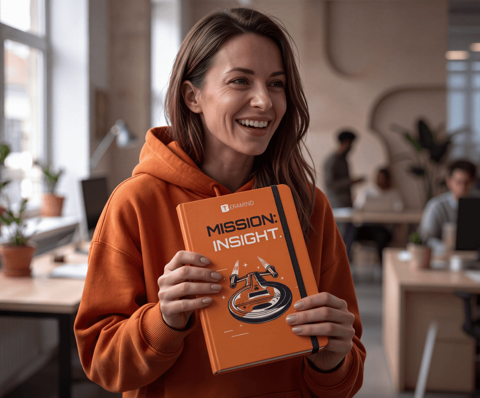 A smiling team member holding the orange Mission: Insight brand book in the office.